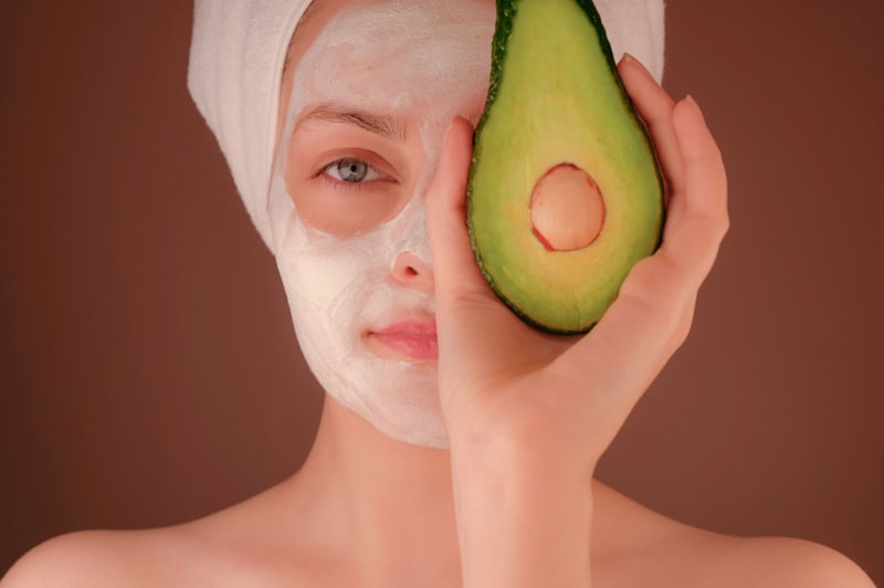 Fresh avocado beside a nourishing plant-based face treatment