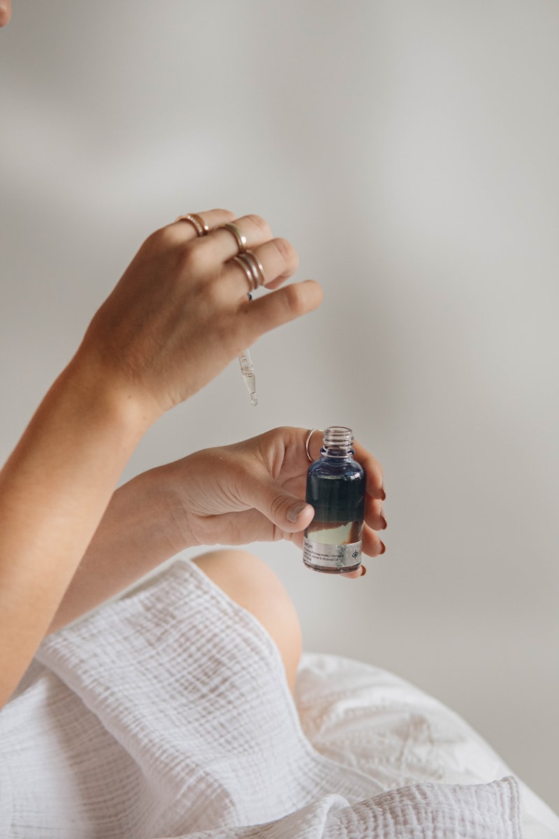 Hands applying a plant-based serum with a glass dropper